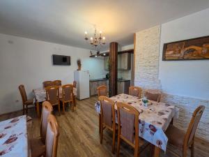 a dining room with tables and chairs and a kitchen at Guest House Bunčić Rooms & Apartments in Slunj