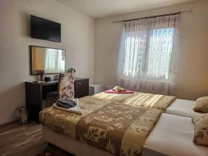 a bedroom with a bed and a desk and a window at Guest House Bunčić Rooms & Apartments in Slunj