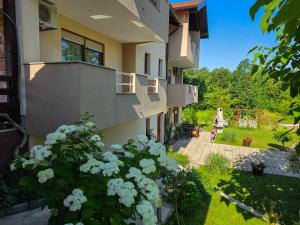 a building with a balcony and flowers in a yard at Guest House Bunčić Rooms & Apartments in Slunj