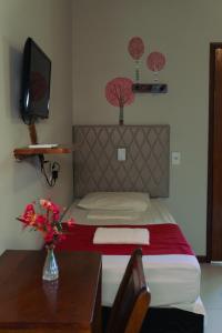 a bedroom with a bed and a table with a vase of flowers at Pousada Munguba in Jericoacoara