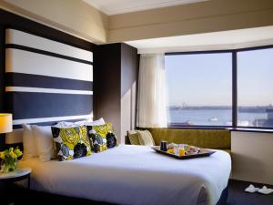 a hotel room with a bed with a tray of food on it at Mövenpick Hotel Auckland in Auckland