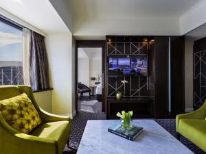 a living room with a couch and a tv at Mövenpick Hotel Auckland in Auckland