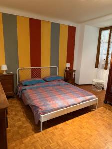 a bedroom with a bed with colorful striped walls at Casa Fulvia by Lago Maggiore Rentals & Estate in Cannobio +6 photos