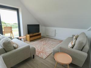a living room with two couches and a television at Glynllifon 9 in Llanallgo