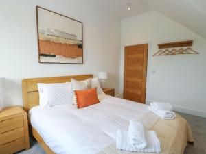 a bedroom with a large white bed with an orange pillow at Glynllifon 9 in Llanallgo