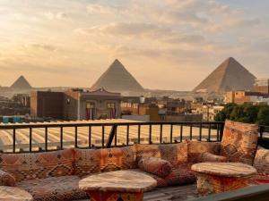 a couch on a balcony with pyramids in the background at Explore Pyramids View in Cairo