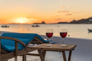 two glasses of red wine sitting on a table with a chair at Pera Milos villa in Pollonia +47 photos