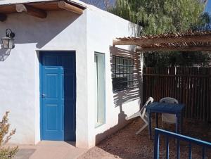 a blue door on a white house with a table at Cabañas don Julio in Maimará