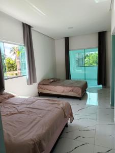 two beds in a room with two windows at Pousada Natural Hostel in Maragogi +83 photos