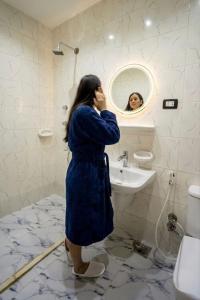 a woman standing in a bathroom looking at herself in the mirror at Explore Pyramids View in Cairo