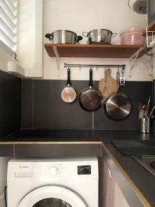 a kitchen with a washing machine and pots and pans at Studio paisible avec jardin in Rémire-Camp