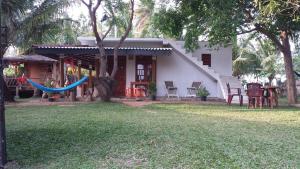 a house with a hammock in front of a yard at Yaye Guest House in Tissamaharama