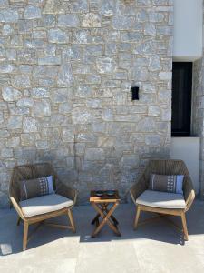 two chairs and a coffee table in front of a stone wall at Villa Hillside Skiathos in Skiathos +34 photos