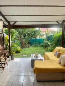 a patio with a yellow couch and a table at Studio paisible avec jardin in Rémire-Camp
