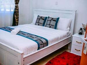 a bedroom with a white bed and a red rug at Homes By Vee in Eldoret