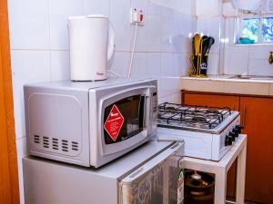 a microwave sitting on top of a refrigerator in a kitchen at Homes By Vee in Eldoret