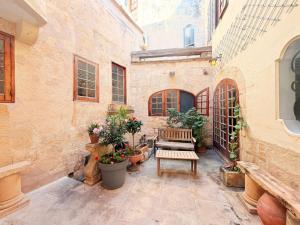 a courtyard with a bench and potted plants at Charming 450-Year-Old House with Pool in Naxxar in Naxxar