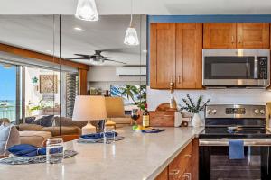 a kitchen with wooden cabinets and a living room at Lahaina Roads 306 in Lahaina