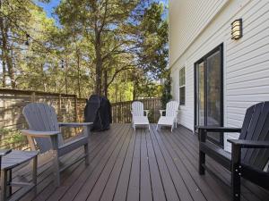 a deck with white chairs and tables on a house at Dune Our Thing in Blue Mountain Beach