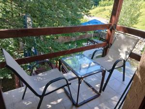 two chairs and a glass table on a balcony at Savnik moutain appartement in Šavnik