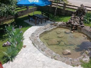 a small pond with a bench and an umbrella at Savnik moutain appartement in Šavnik