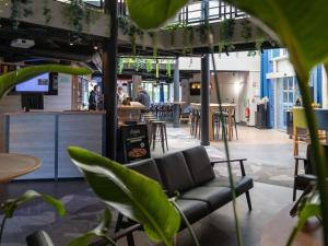 a living room with a couch and tables and chairs at Ibis Styles Evry Lisses Paris Sud in Courcouronnes