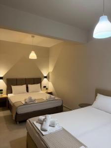 a bedroom with two beds and two towels on a table at Laki Hotel in Nea Plagia