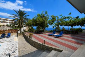 a patio with blue chairs and trees and the ocean at Galini Apartments in Achlia