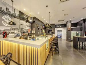 a restaurant with a counter with chairs and tables at ibis Sydney World Square in Sydney