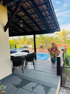 a wooden deck with a table and chairs and a pool at Casa Brisa Escarpas in Capitólio +34 photos