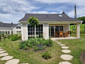 a white house with a table and chairs in a yard at Seventh Heaven Village Glamping in Rogašovci