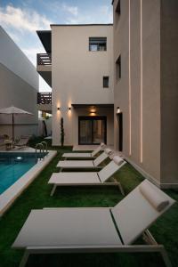 an external view of a building with white chairs and a pool at Sea Salt Skiathos in Skiathos