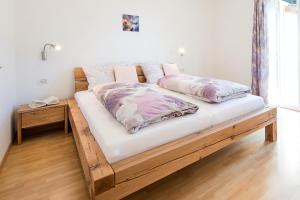 a wooden bed with two pillows on it in a room at Haus Dorfblick in Caldaro
