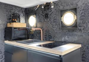a kitchen with a sink and a stove and two windows at Love Room sur l'eau & Rooftop in Asnières-sur-Seine
