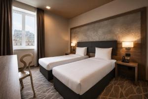 ein Hotelzimmer mit zwei Betten und einem Fenster in der Unterkunft Radisson Hotel City Centre Odesa in Odessa