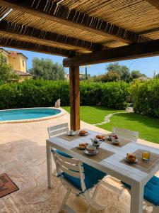 a white table and chairs under a pergola next to a pool at Casa Vacanza Li Menduli San Teodoro in San Teodoro