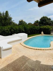 a swimming pool with a white couch and a white bench at Casa Vacanza Li Menduli San Teodoro in San Teodoro