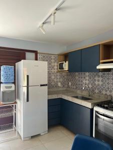 a kitchen with a white refrigerator and blue cabinets at Maruá - Brisa e Sossego em Touros in Touros