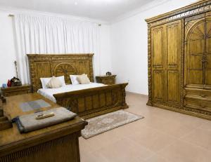 a bedroom with a bed and a large wooden cabinet at Simple Beach Stay 100m to Dahariz Beach Salalah in Salalah
