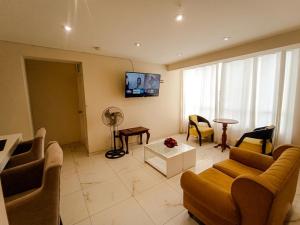 a living room with a couch and a tv on the wall at Hospedaje & Minidepas VALERY in Trujillo