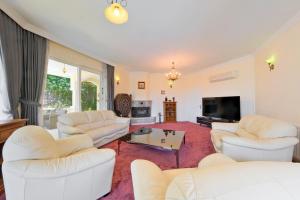 a living room with white couches and a tv at Private Pool Villa with Garden & Forest View in Fethiye