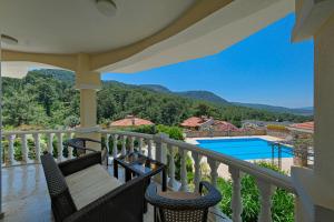 a balcony with chairs and a view of a swimming pool at Private Pool Villa with Garden & Forest View in Fethiye
