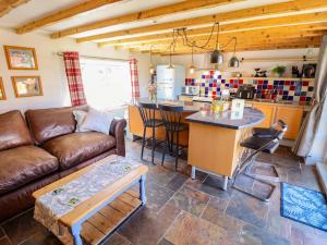 a living room with a brown couch and a kitchen at Gables Cottage in Market Rasen