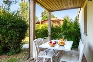 a table and chairs on the porch of a house at Résidence Pierre & Vacances Les Cottages Du Lac in Parentis-en-Born
