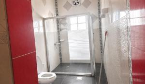 a bathroom with a toilet and a glass shower at Simple Beach Stay 100m to Dahariz Beach Salalah in Salalah