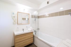 a white bathroom with a sink and a shower at Résidence Pierre & Vacances Les Cottages Du Lac in Parentis-en-Born