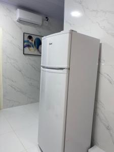 a white refrigerator in a kitchen next to a wall at APTO - Espaço Vix II in Vitória