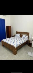 a bedroom with a wooden bed with blue and white sheets at La belle vie in Rufisque