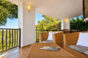 a patio with wicker chairs and a table on a balcony at Catalina, ritorno al '70 tra mare e natura in Cannigione