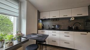 a kitchen with white cabinets and a black table at Studio w kamieniczce in Konstantynów Łódzki
